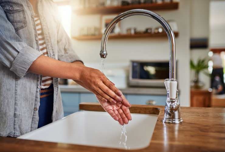 persona che si lava le mani in cucina