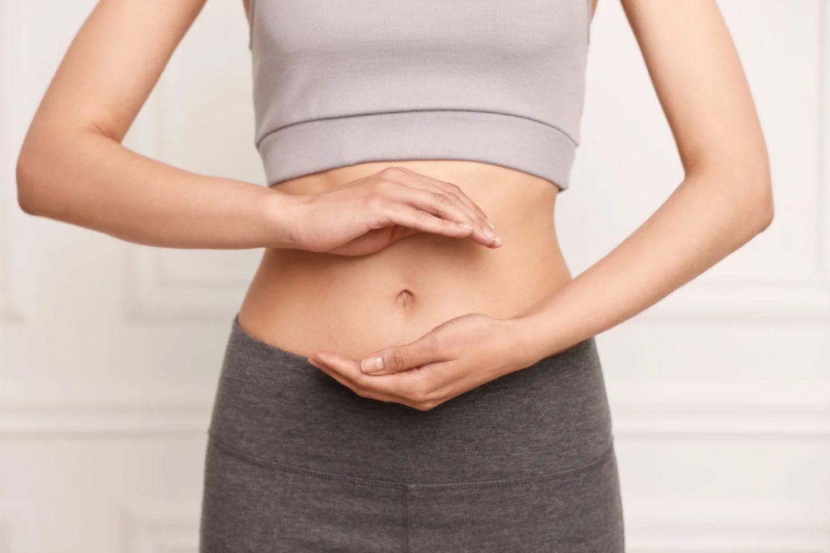 donna con la pancia scoperta e le mani sopra e sotto all'ombelico