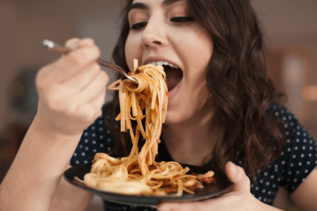 donna che mangia delle tagliatelle al sugo