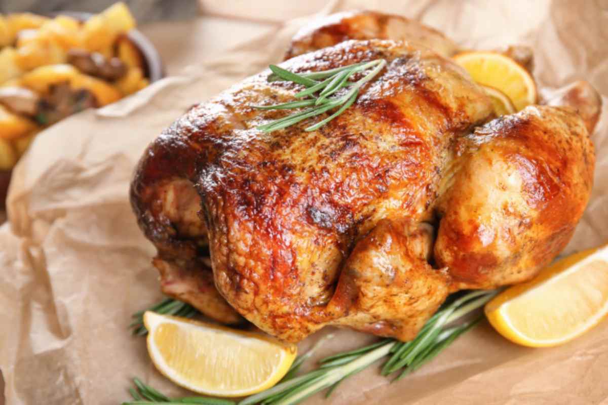 pollo arrosto con accanto degli spicchi di limone e del rosmarino
