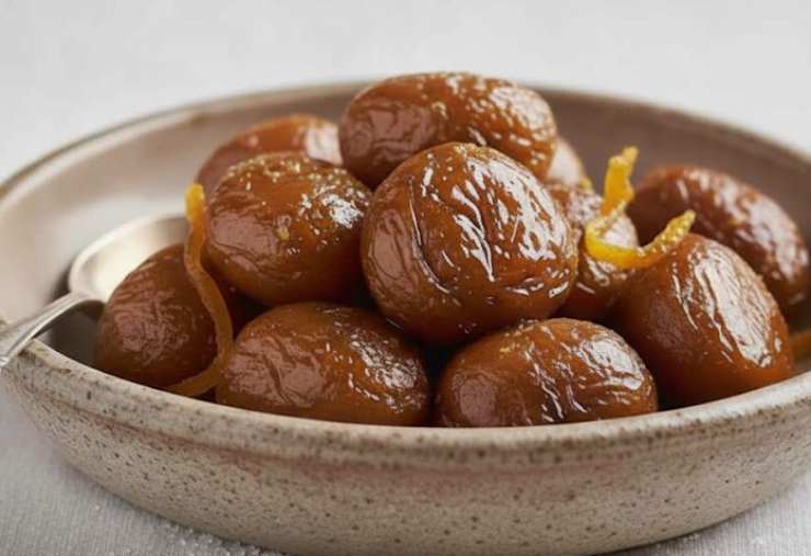 castagne caramellate in piatto con scorze di arancia
