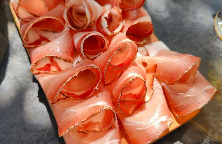 Fettine di speck su un tagliere