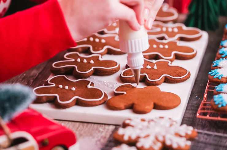 mani che decorano biscotti di natale con glassa