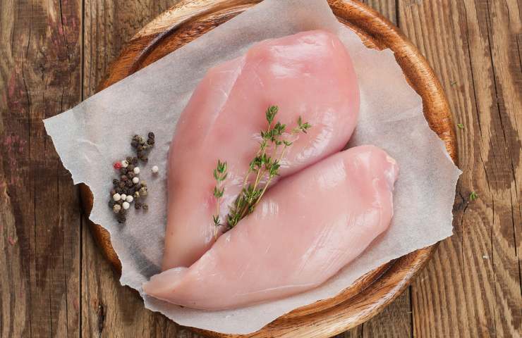 Due petti di pollo in un piatto di legno