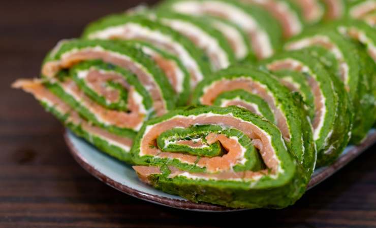 piatto con rotolo di spinaci farcito con formaggio e salmone a fette