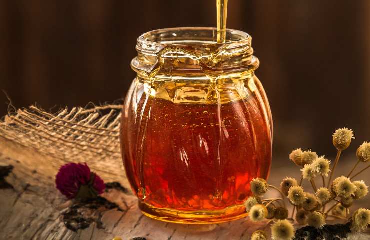 Barattolo di miele su sfondo di legno