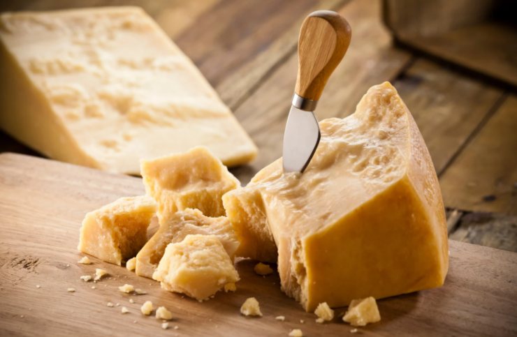 pezzo di formaggio grana sopra ad un tagliere 