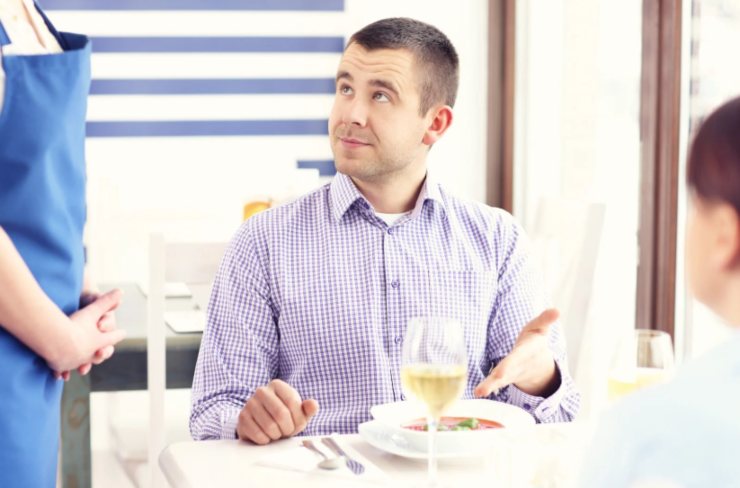 uomo seduto al tavolo del ristorante che si lamenta con la cameriera