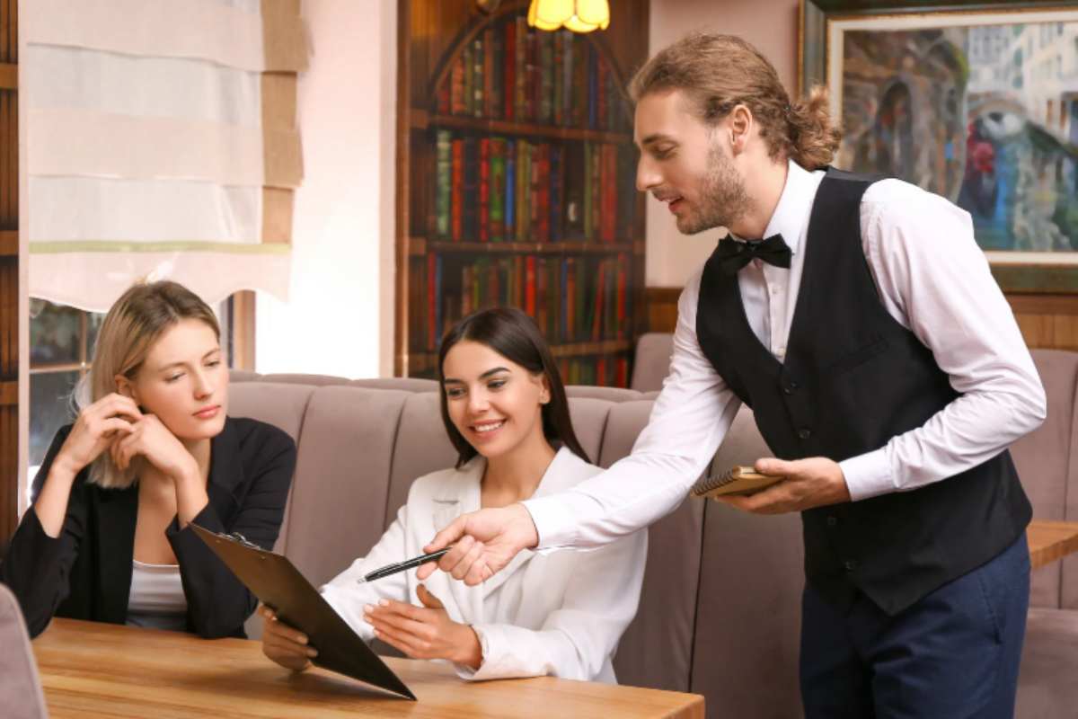 cameriere che indica a due clienti qualcosa sul menù
