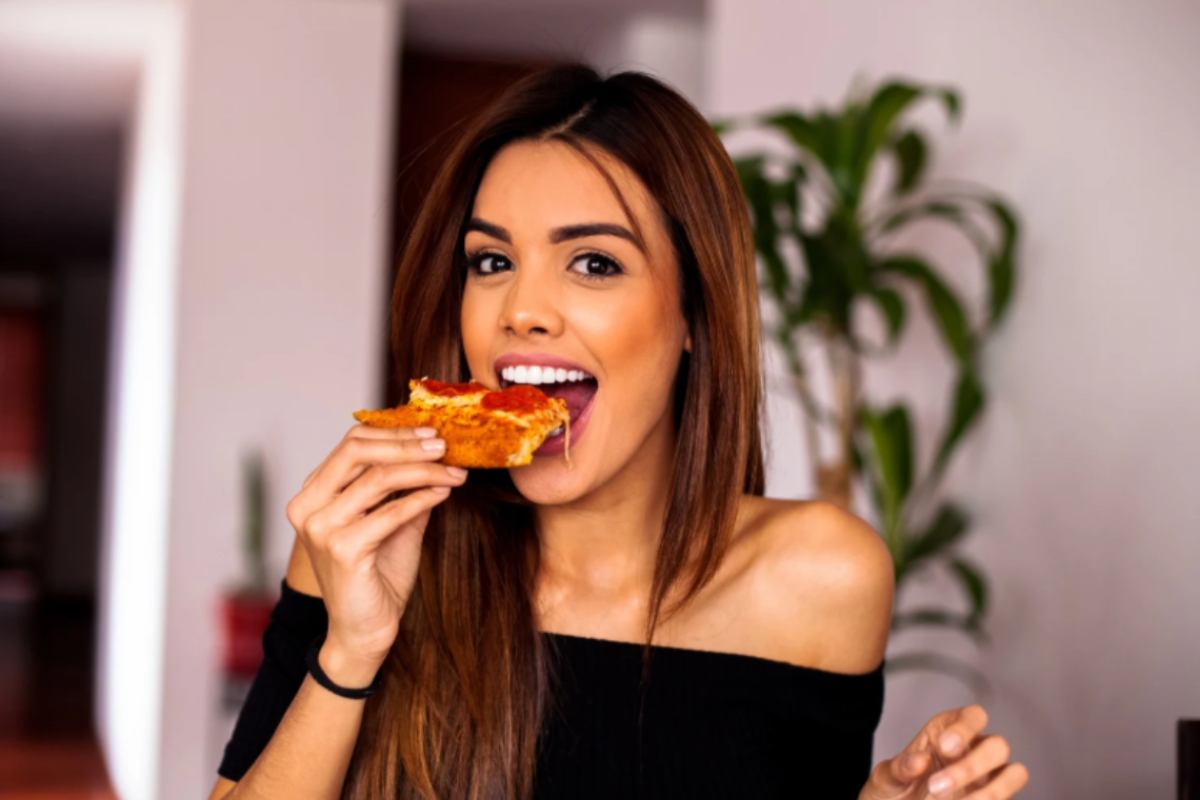 donna che mangia una fetta di pizza