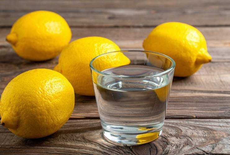 bicchiere con acqua e limoni sparsi sul tavolo