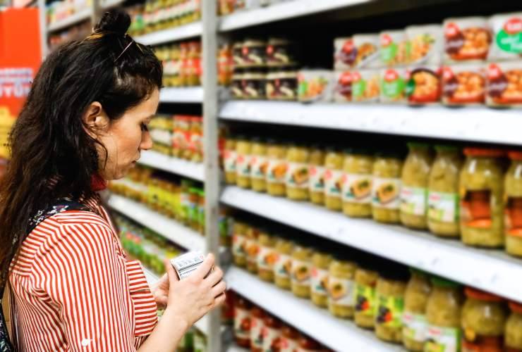 donna al supermercato con un prodotto in mano