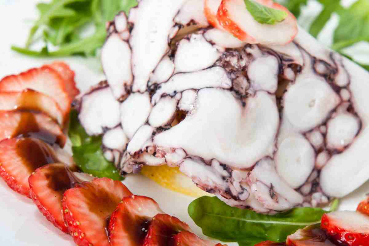 fettina sottile di carpaccio di polpo decorata con fettine di fragole e aceto balsamico