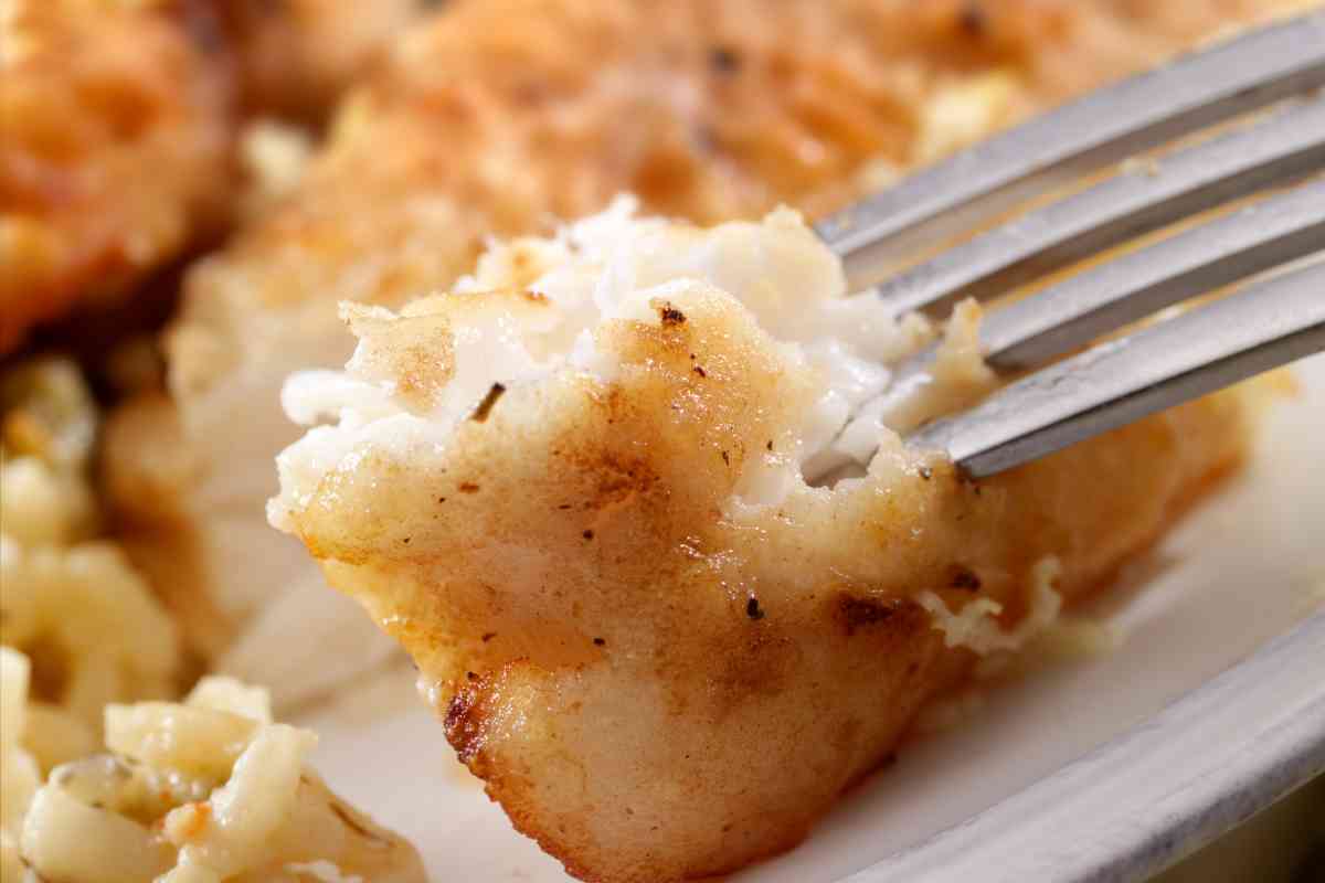 una forchetta infilza un pezzo di gallinella in padella