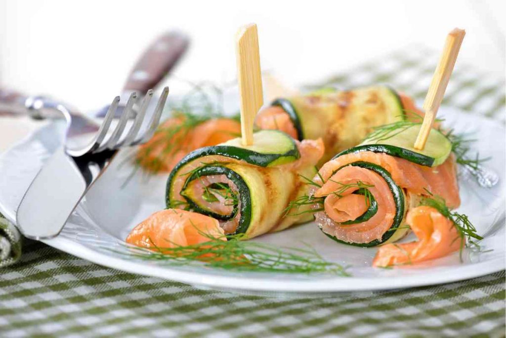 un piatto con dentro gli involtini di salmone e zucchine fermati con uno stecchino