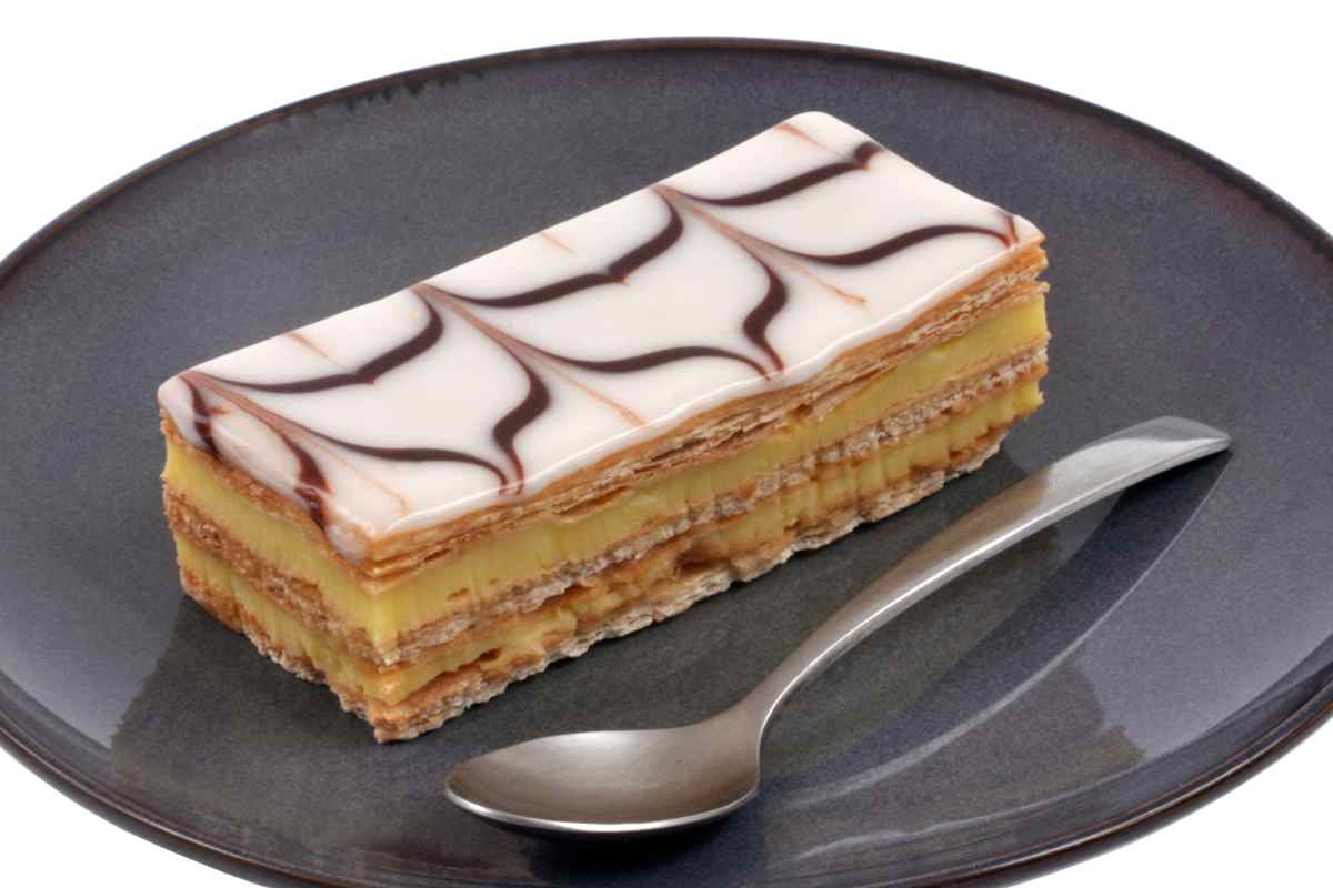 Una fetta di torta millefoglie alla crema pasticciera a ragnatela in un piatto