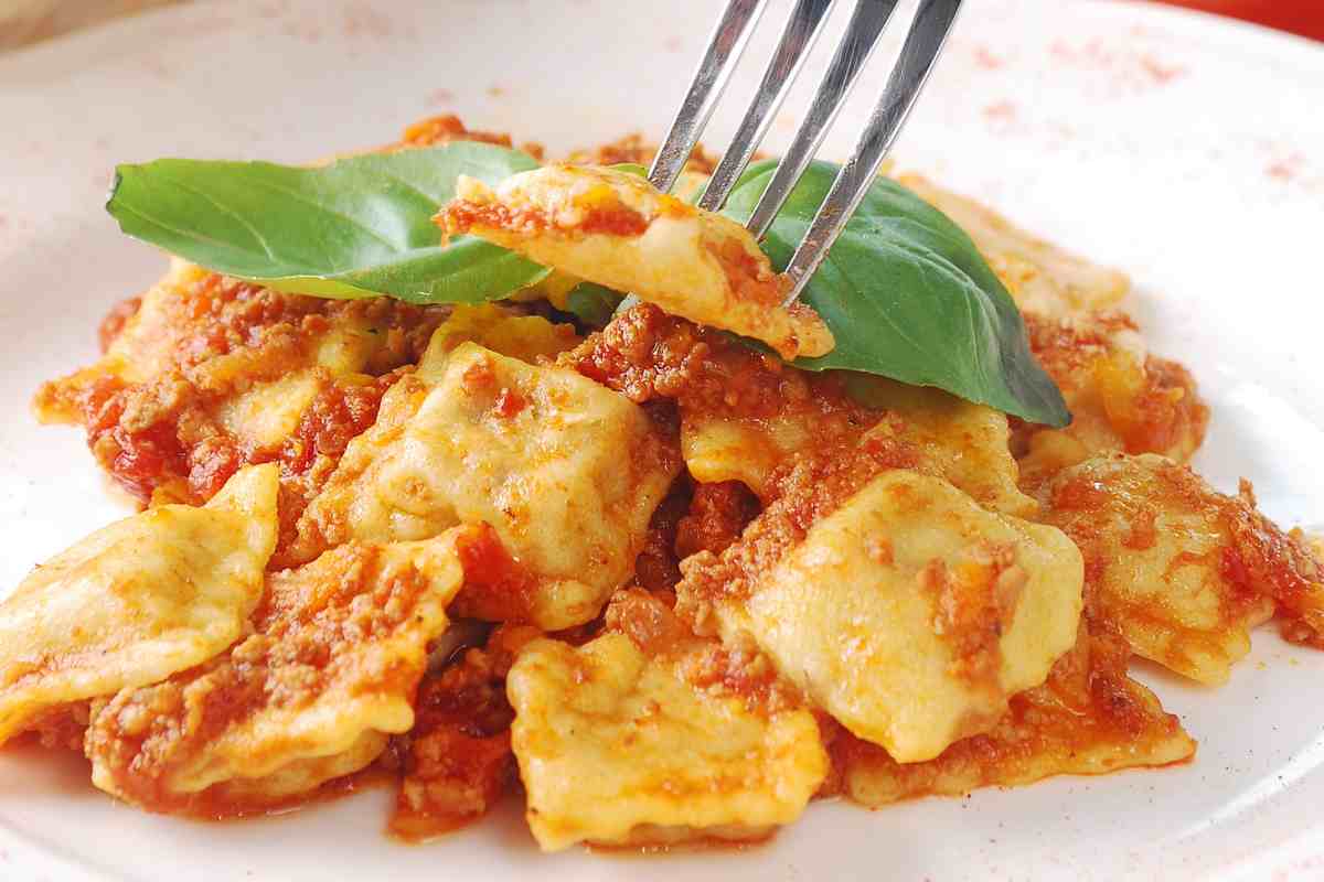 un piatto con dentro i ravioli di brasato conditi con sugo di carne