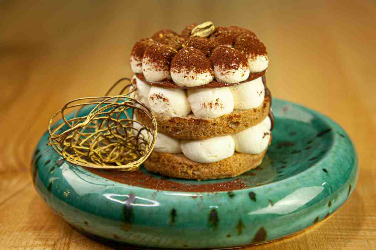 Tiramisù senza mascarpone di forma rotonda su un piattino verde