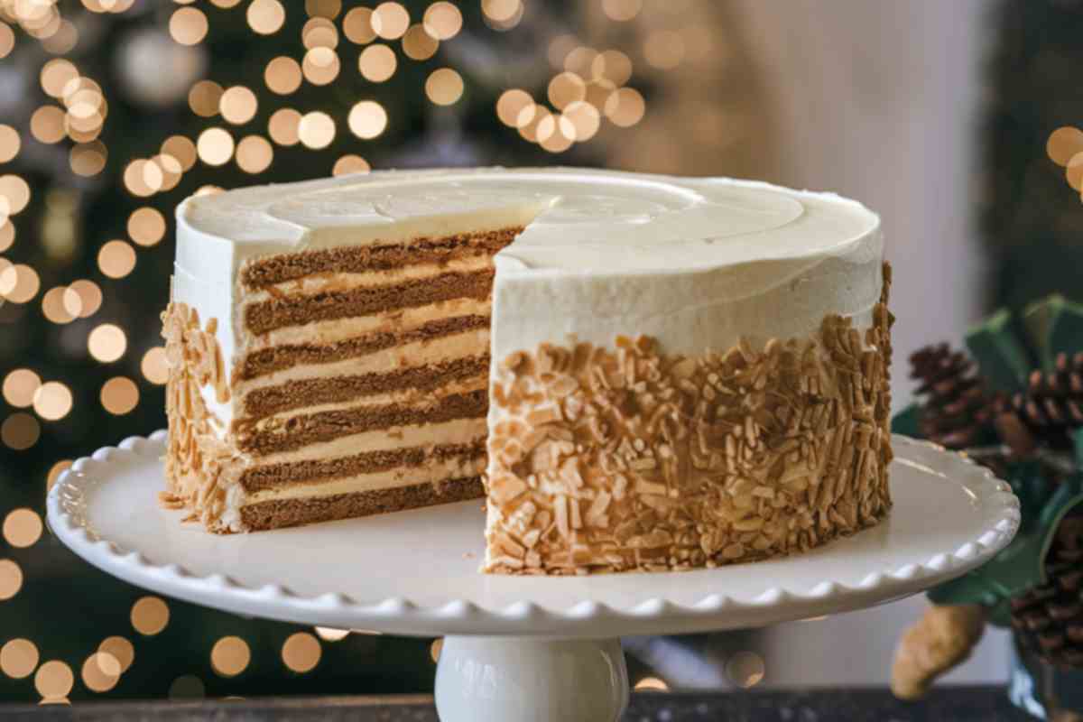 torta al pan di zenzero multistrato con crema al formaggio e mandorle tostate su una alzatina con sfondo natalizio