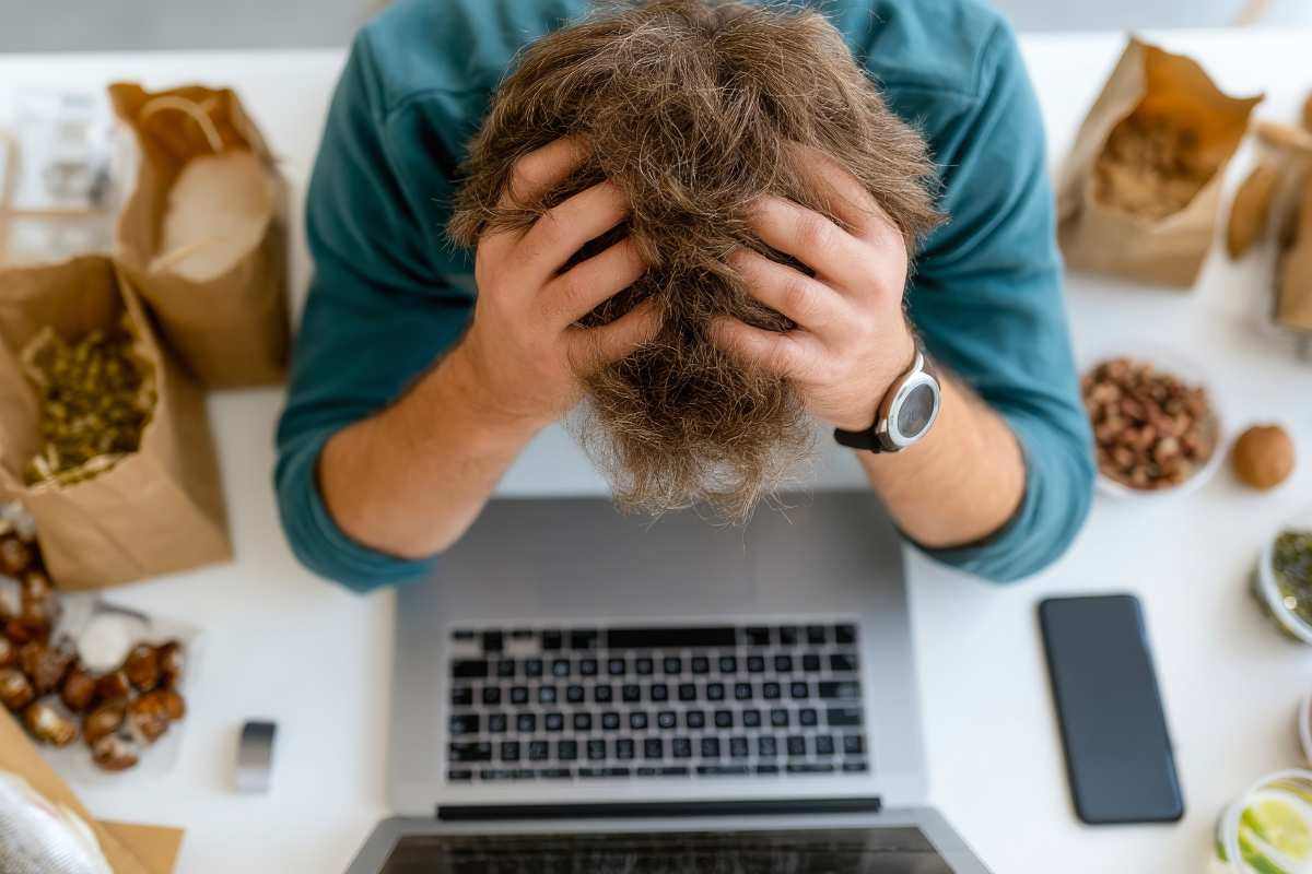 uomo al pc con le mani sulla testa