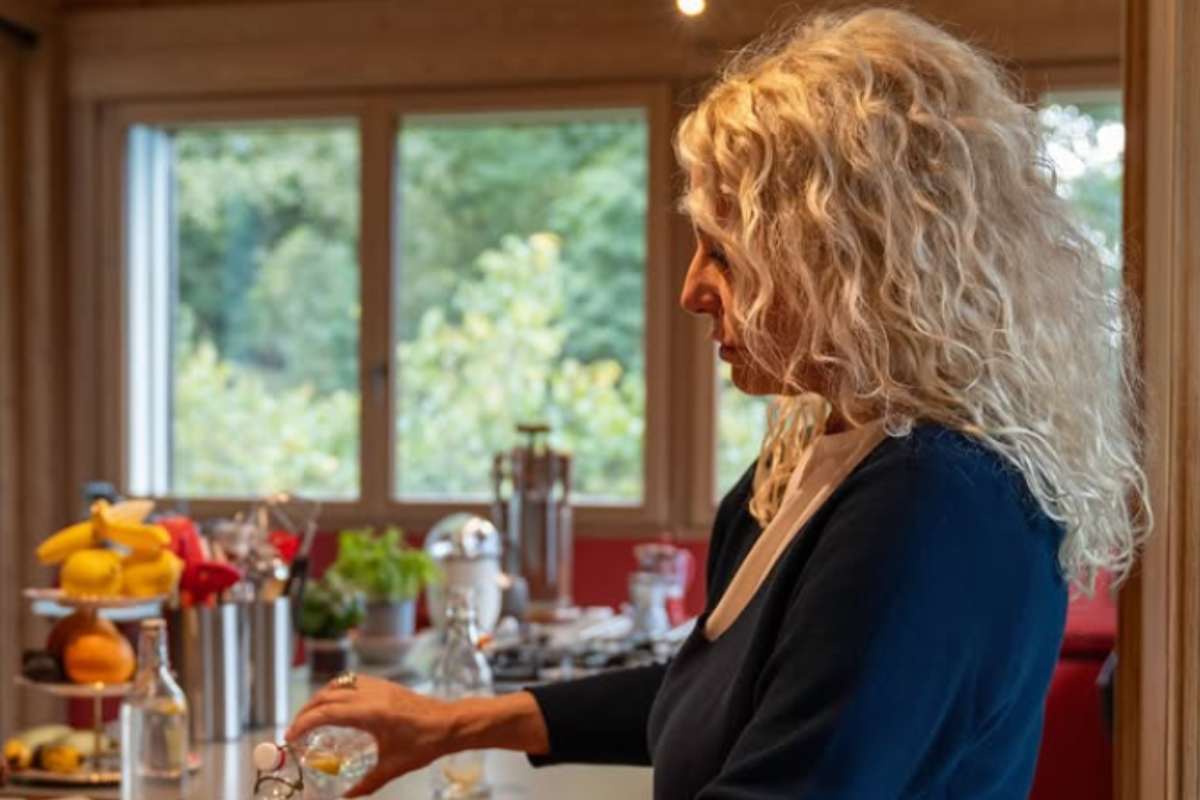 antonella clerici di profilo mentre versa dell'acqua in un bicchiere nella cucina di casa sua