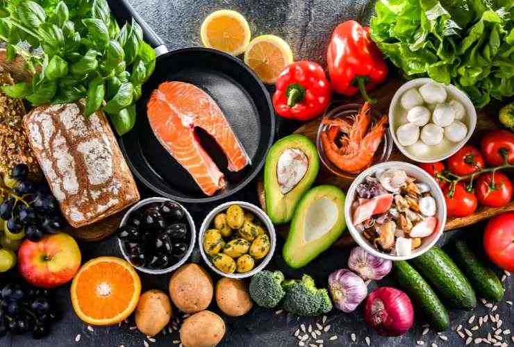 alimenti vari sul tavolo: salmone, avocado, frutta, verdura