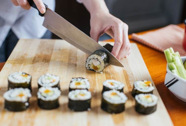 persona che prepara i roll di sushi