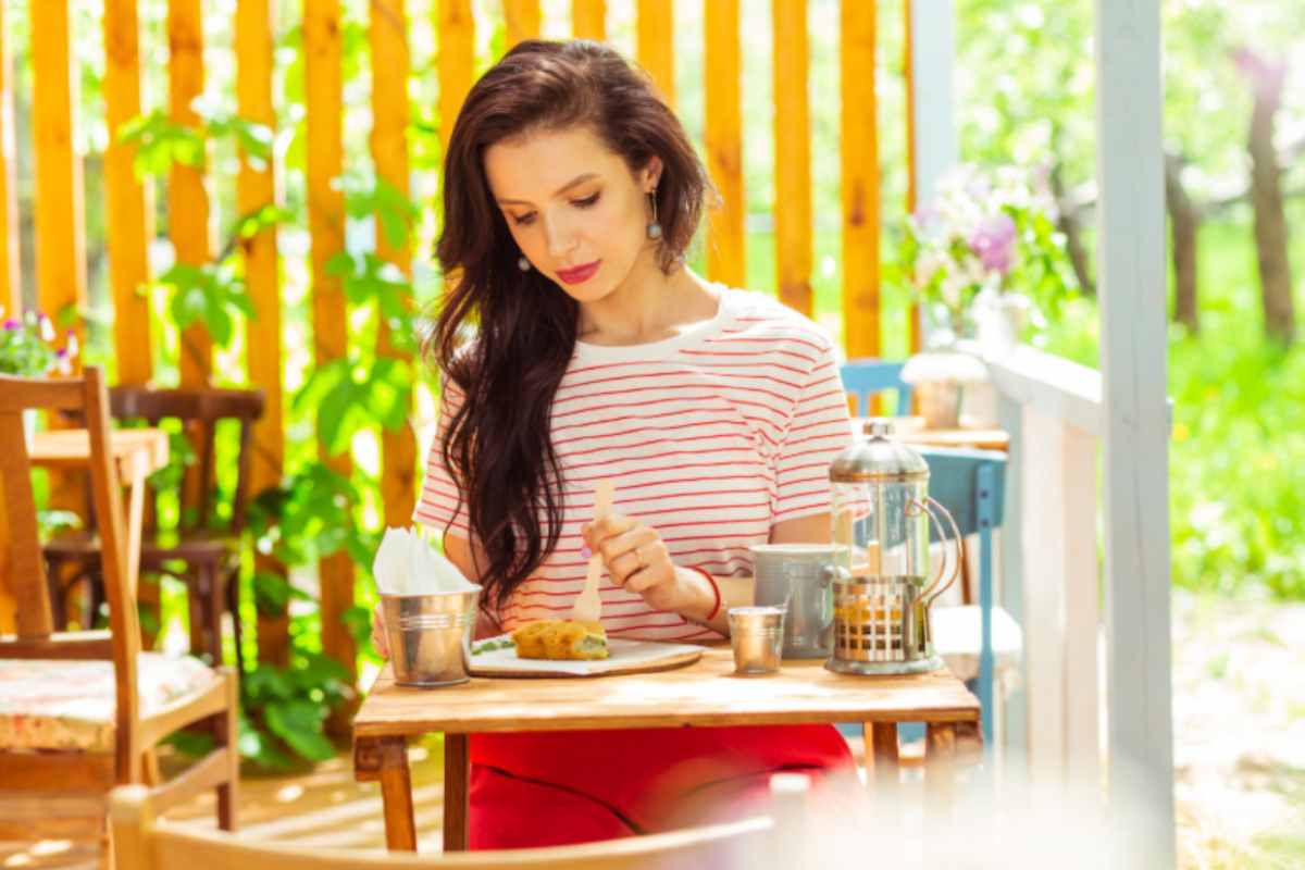 donna che mangia sola in un locale all'aperto