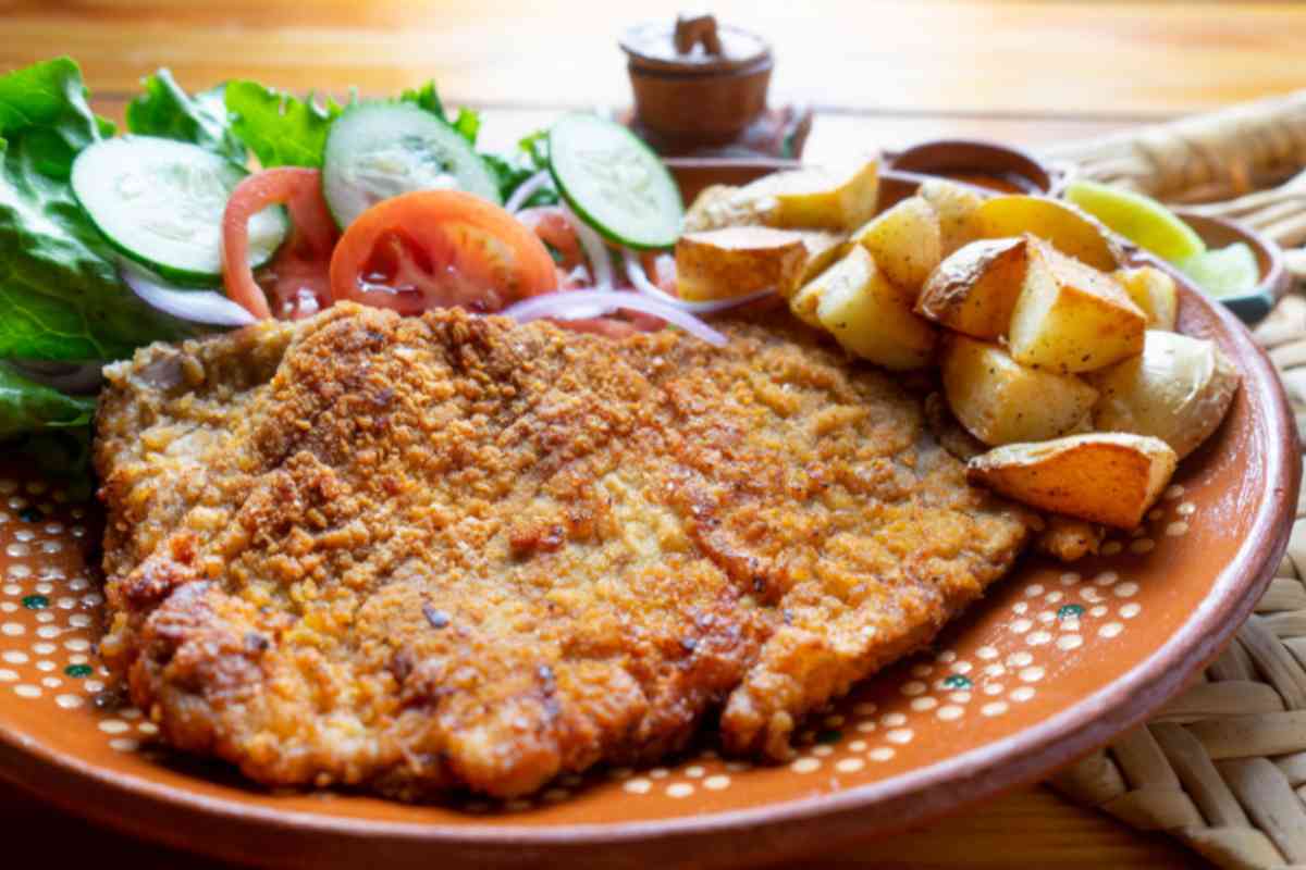 cotoletta alla milanese con contorno di insalata e patate al forno