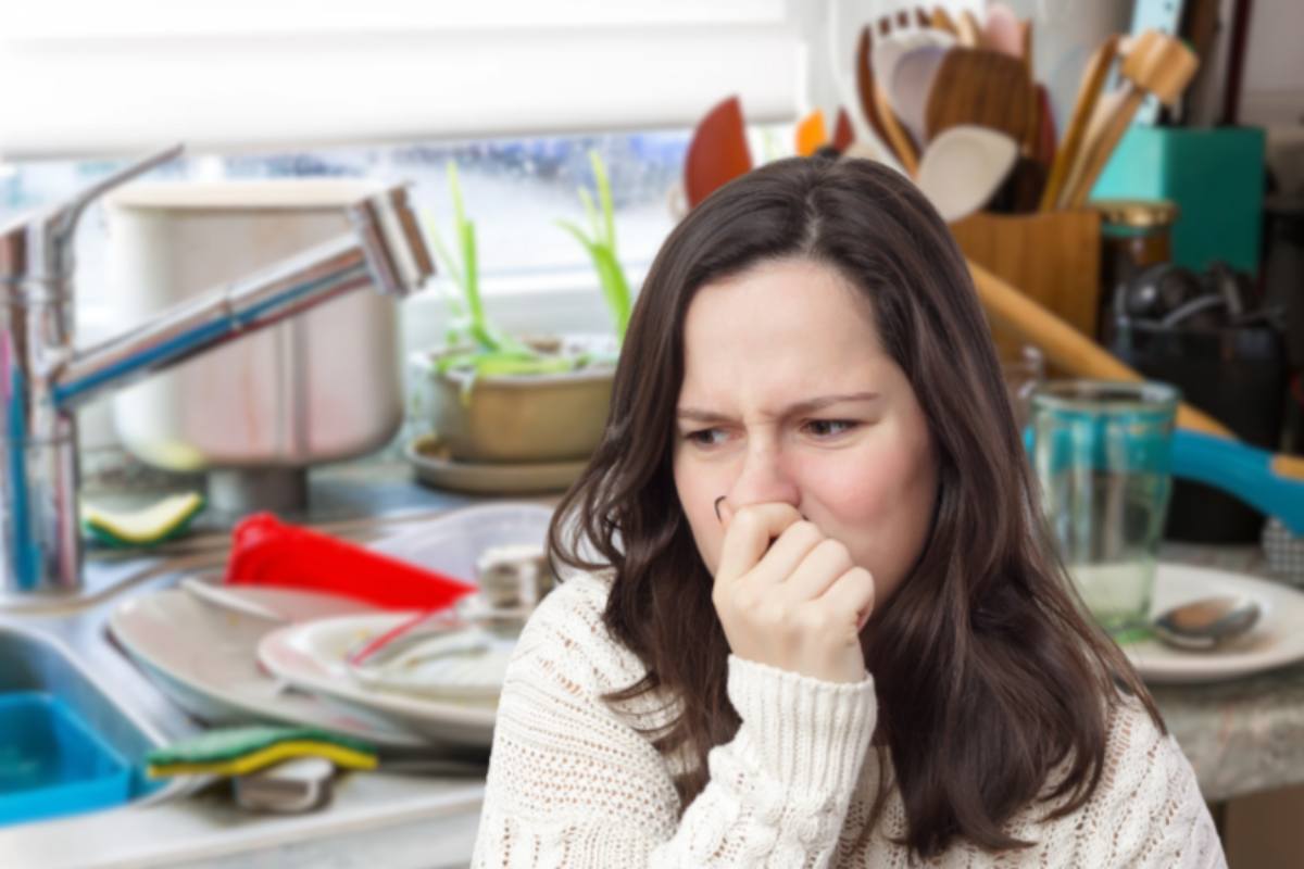 donna che sente puzza e cucina sporca sullo sfondo