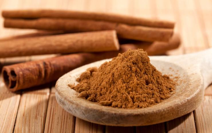 stecche e polvere di cannella su tavolo di legno