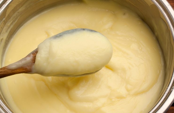 Crema pasticciera liscia e senza grumi in una pentola con un mestolo di legno