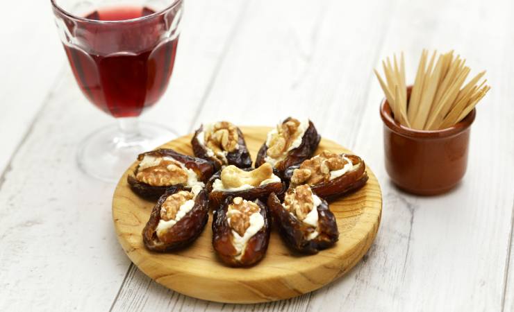 tagliere con datteri ripieni di formaggio e noci