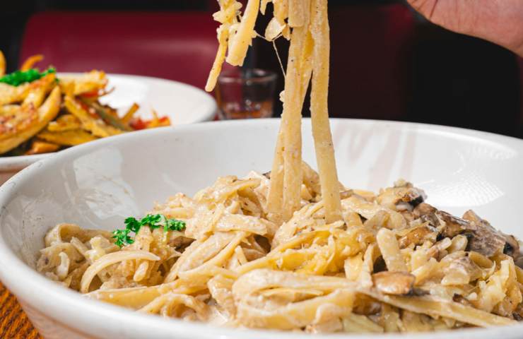 Un piatto di fettuccine cremose allo zafferano con funghi