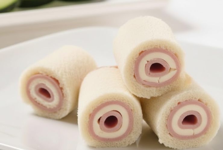 girelle di tramezzini con prosciutto e formaggio in piatto bianco