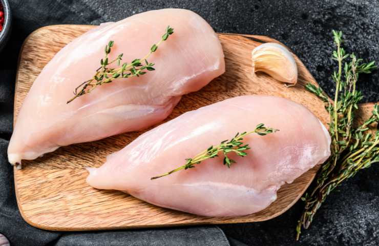 Petti di pollo su un tagliere di legno
