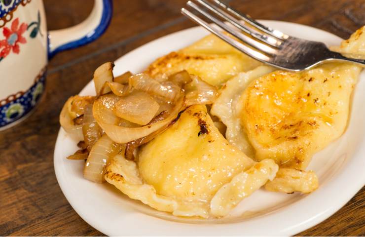 ravioli con ripieno di patate e cipolle rosolate in un piatto su tavolo di legno