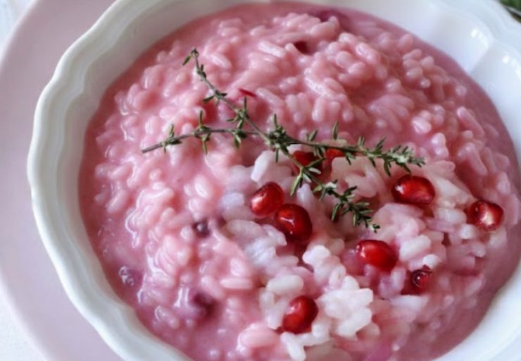 primo piano di risotto alla melagrana in piatto bianco
