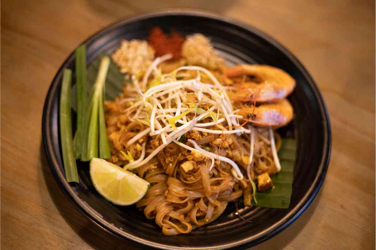 tagliatelle con gamberi, germogli di soia e verdure in un piatto scuro