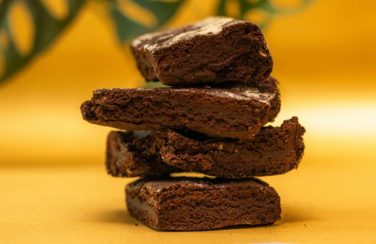 Fette di torta tenerina posizionate le une sulle altre su un piano giallo