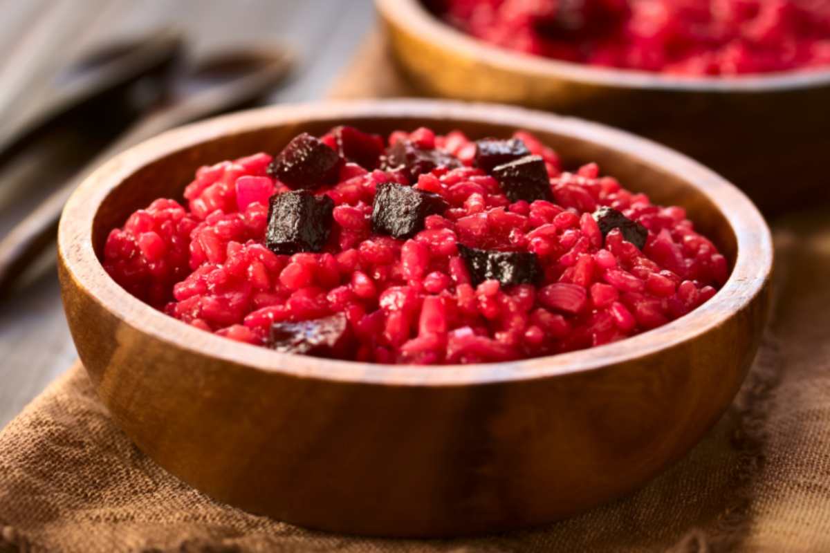 risotto alla barbabietola dentro ad un piatto di legno