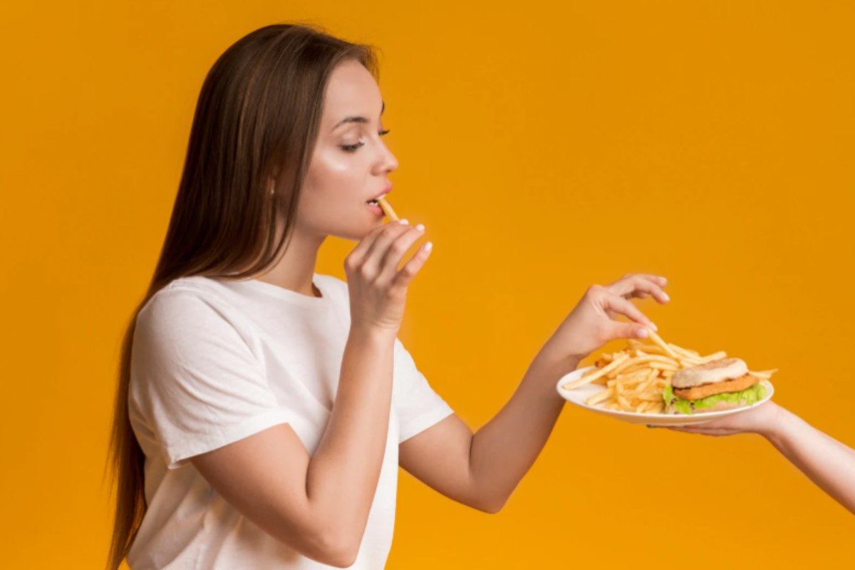 donna che mangia delle patatine fritte e un burger