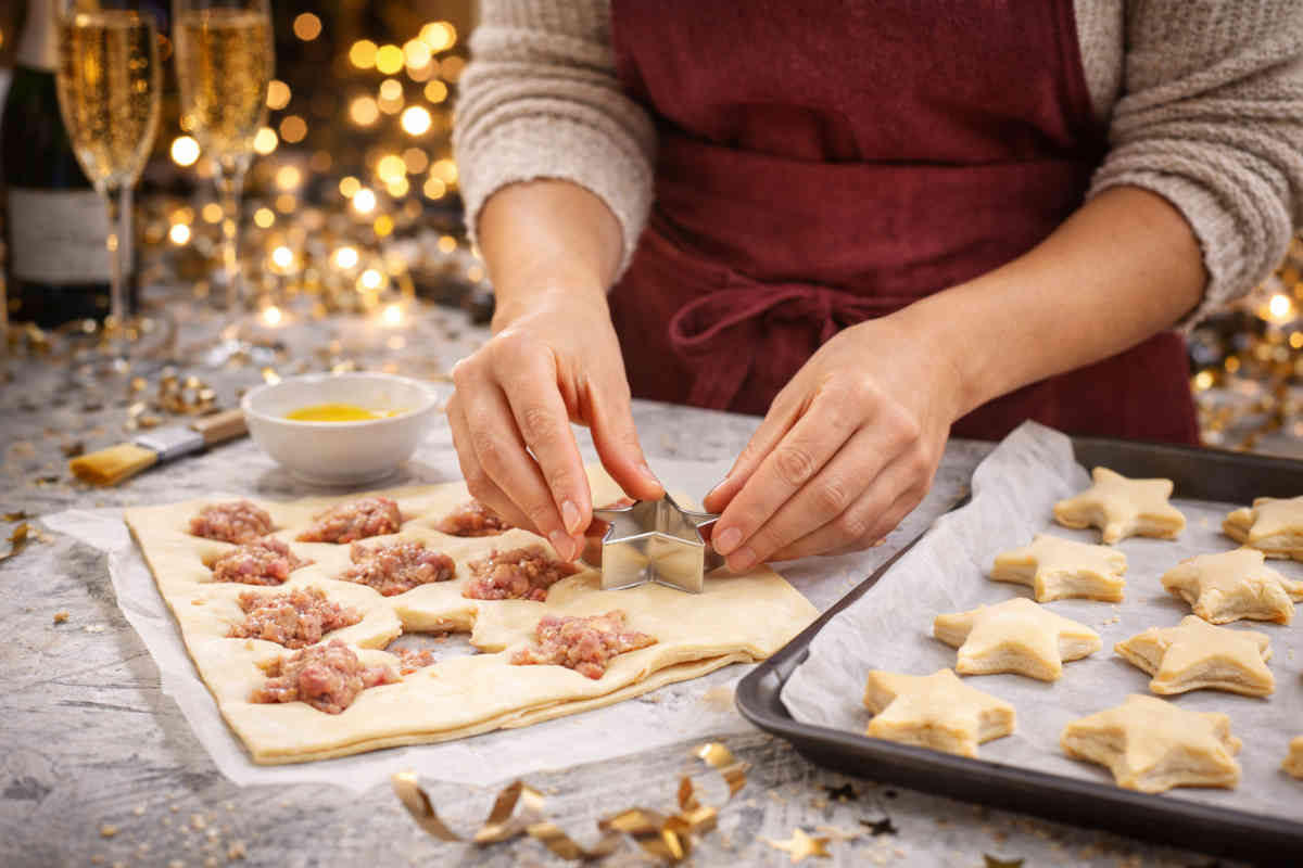 Donna con grembiule che prepara delle stelline sfoglia con cotechino