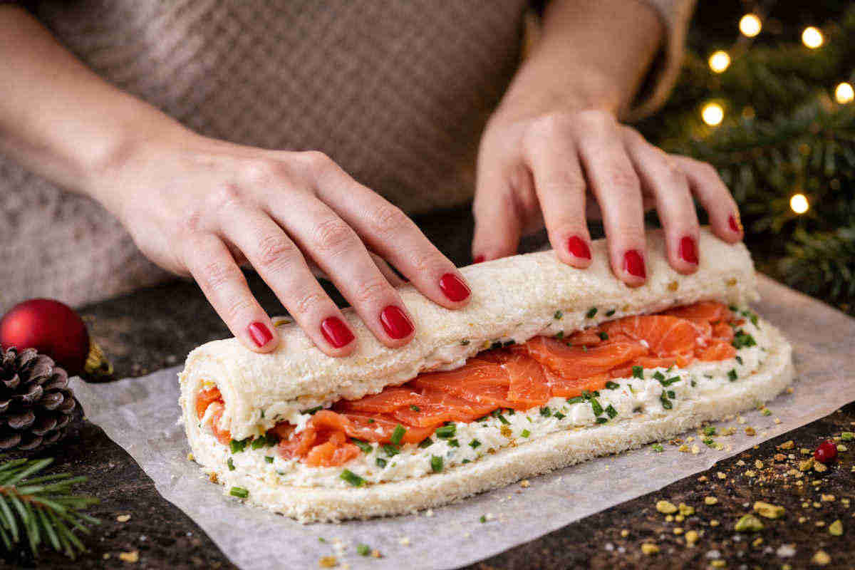 Mani femminili che arrotolano il tronchetto di natale