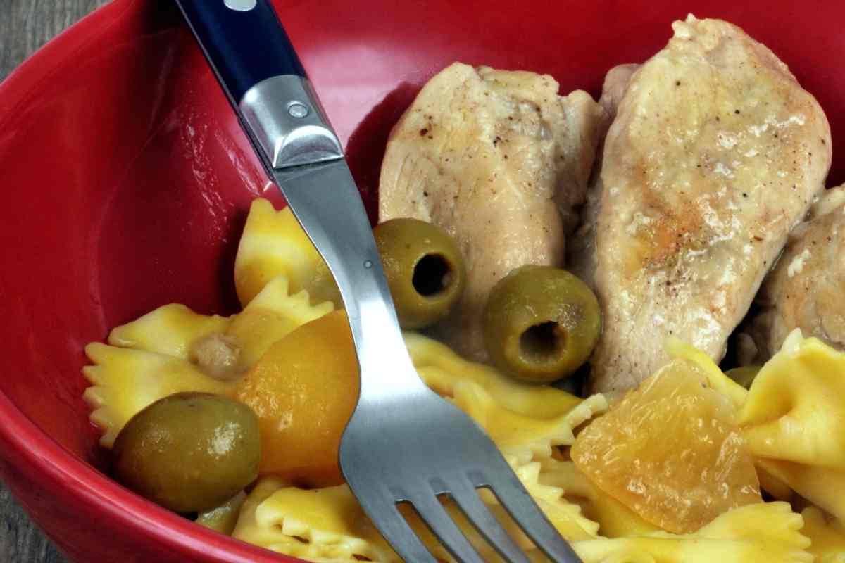 Farfalle pollo ed olive verdi in una terrina con la forchetta