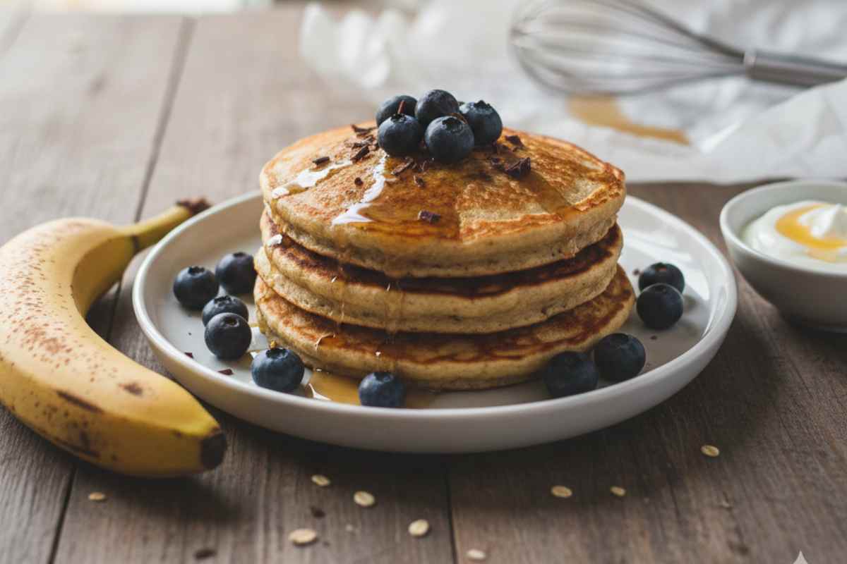 Pancake banana ed avena in un piatto con ingredienti su tavolo di legno