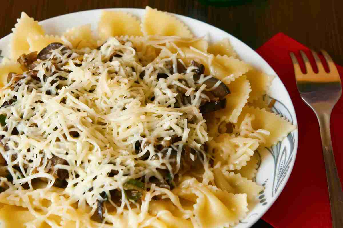 Farfalle spadellate con dadolata di verdure e pioggia di formaggio in un piatto