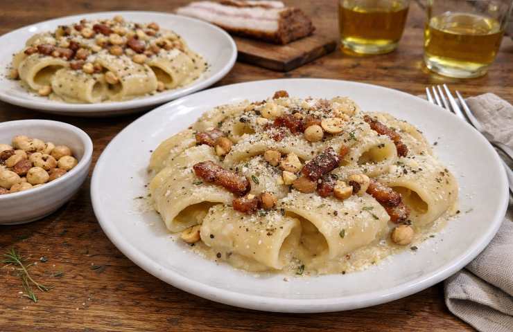 Due piatti di Calamarata lunga con crema di topinambur, guanciale croccante e nocciole