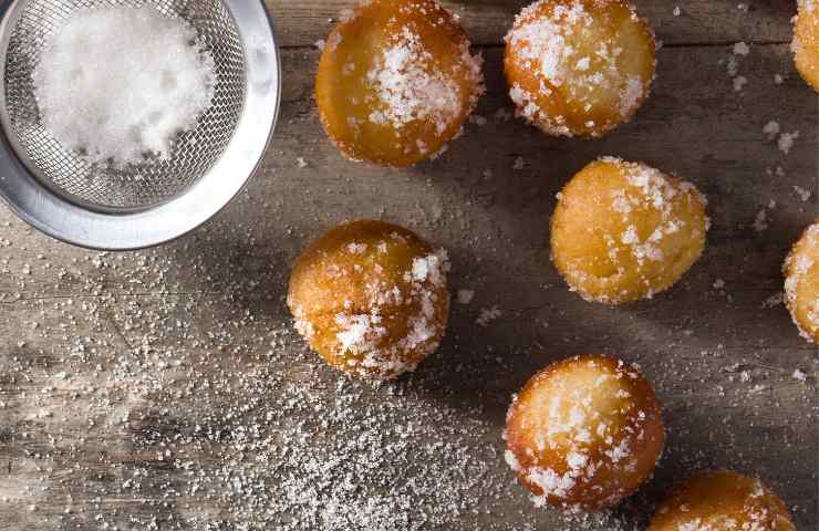 Cinque castagnole di Carnevale soffici su un piano inzuccherato
