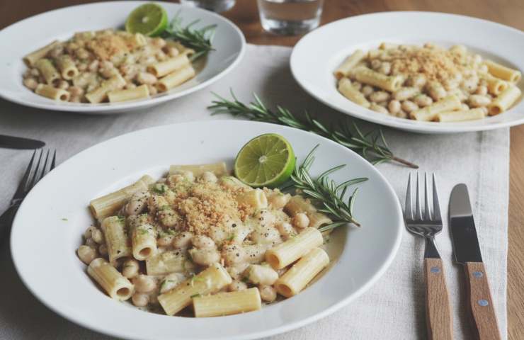 Pasta con Crema di Cannellini, Lime e Rosmarino in tre piatti su tavola con tovaglia bianca